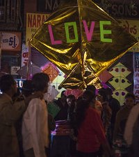 Colourful big shiny golden kite with the word love in the night market or Indian bazaar for the festival of Makar Sankranti or Uttarayan in the old area Khadia of Ahmedabad in Gujarat, India