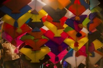 Colourful kites in pink, yellow, orange, green, blue, white colours in the night market or Indian bazaar for the festival of Makar Sankranti or Uttarayan in the old area Khadia of Ahmedabad in Gujarat, India.