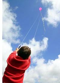 A boy flying a purple 2 line Diamond on a cloudy day.