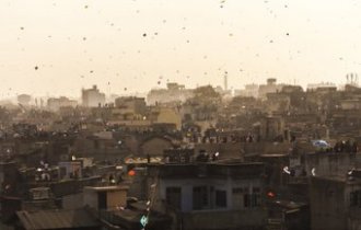 People gathered on terraces or rooftops of their houses everyone flying kites and the sky covered with tiny colourful dots of kites for the festival of Makar Sankranti or Uttarayan in the old Khadia area of Ahmedabad in Gujarat, India.