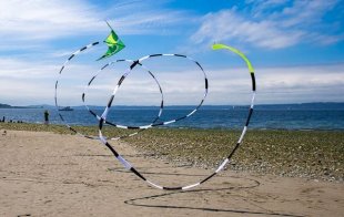 Two line stunt kite in flight with a tail.