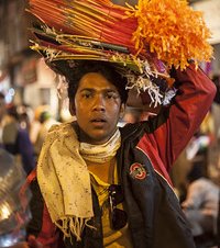 Young boy carrying heaps of kites over his head for selling for the festival of Makar Sankranti or Uttarayan in the old area Khadia of Ahmedabad in Gujarat, India